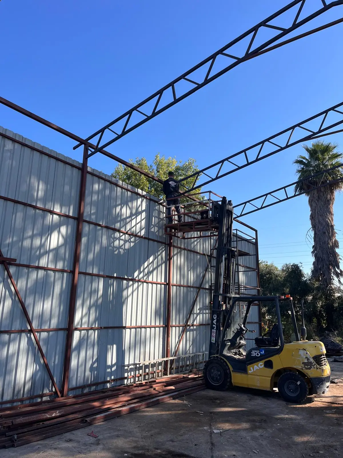 Installing steel trusses with a forklift and work platform.