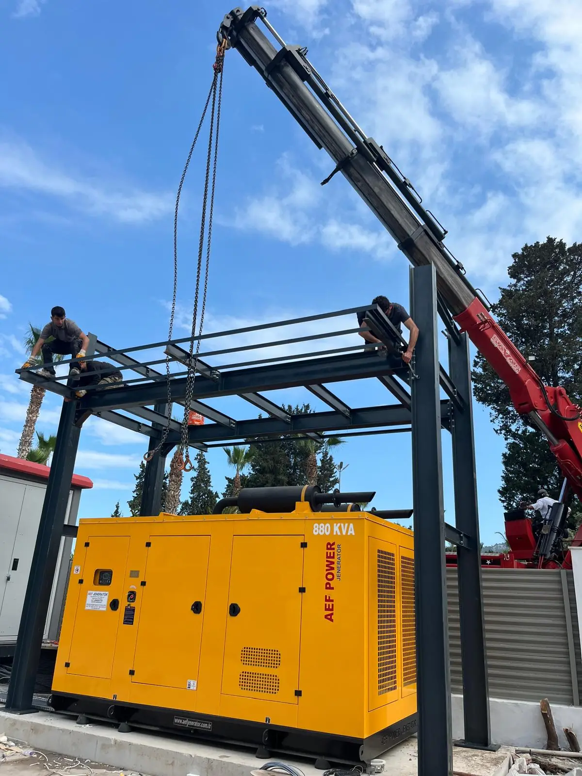Steel platform erected over a generator, with a crane and the crew working on top.